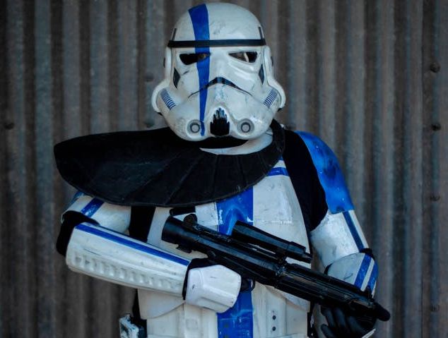 Un hombre vestido como un soldado de asalto sostiene un arma. Figuras coleccionables de Star Wars