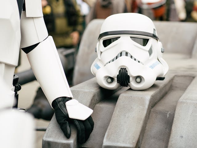 Un casco de stormtrooper junto a un hombre disfrazado de Star Wars